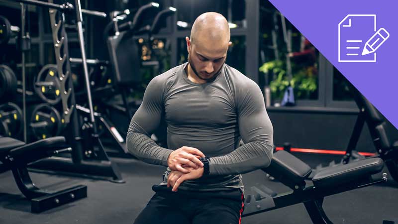 Homem no ginásio a olhar para o relógio